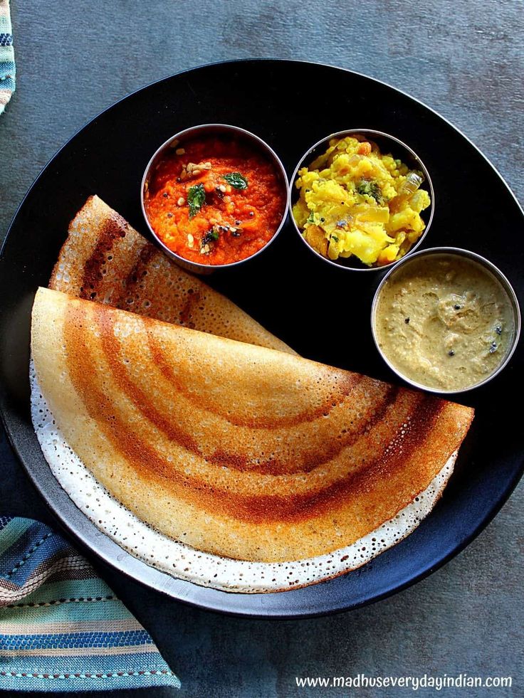 a black plate topped with food and sauces