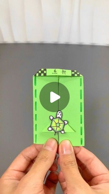 someone is holding up a green origami video game card with a skull and crossbones on it