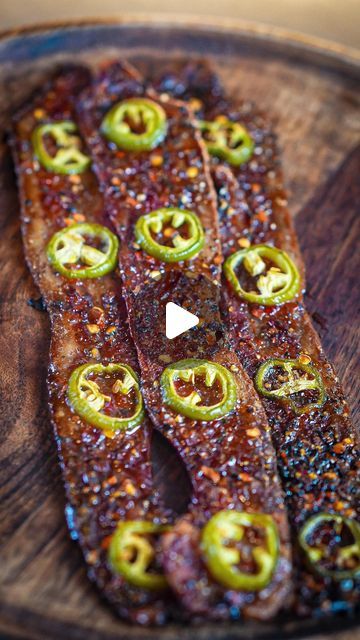 an image of some food on a wooden platter with green peppers and sauces