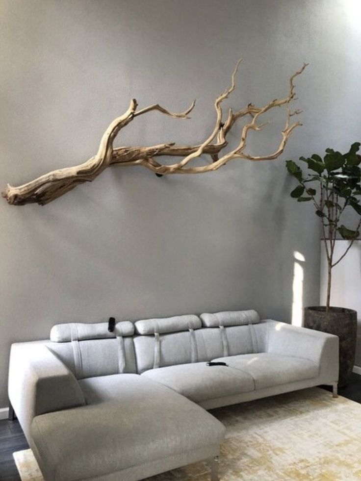 a living room with a white couch and a tree branch on the wall above it