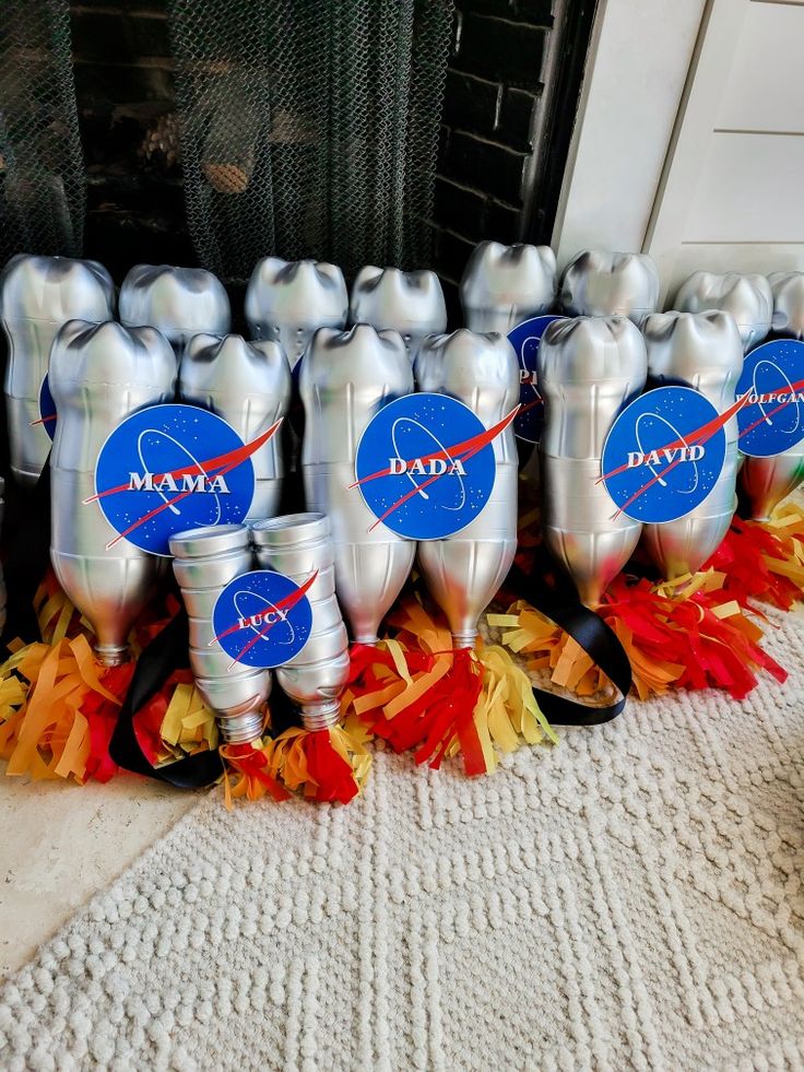 silver cups with nasa stickers on them are lined up in front of a fireplace