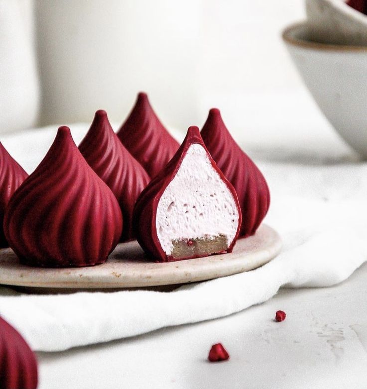 red velvet desserts on a white plate with rose petals around them and a bowl in the background