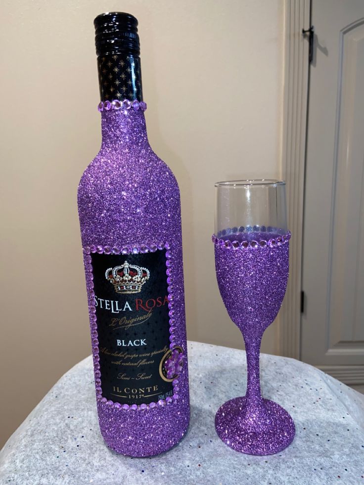 a purple wine bottle next to a glass on a table