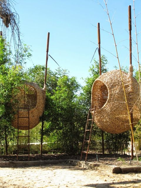 some kind of sculpture made out of straw and bamboo sticks with trees in the background