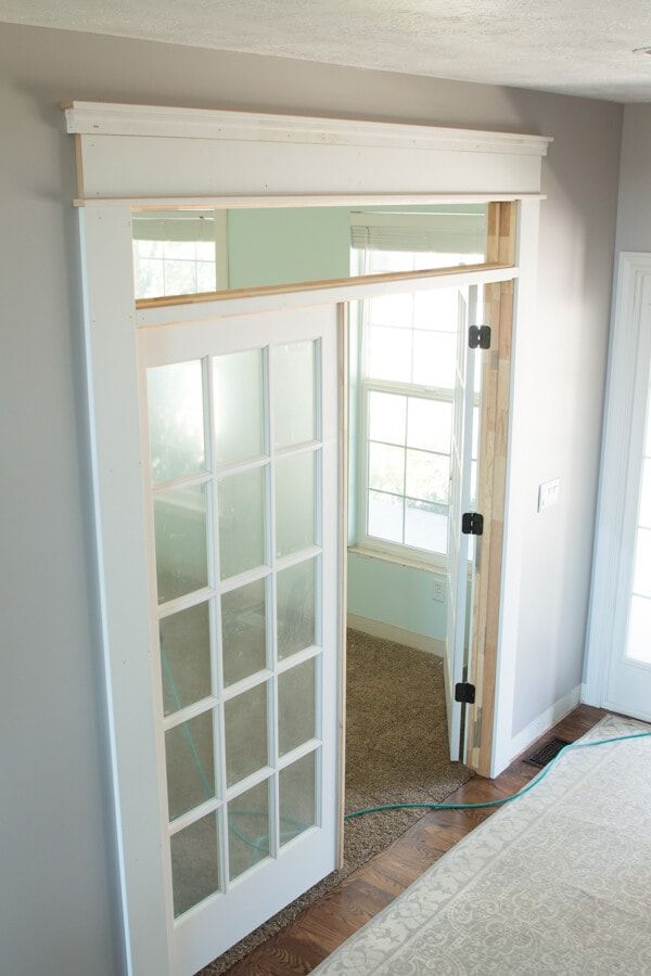 an empty room with a white door and window frame on the wall, in front of a carpeted floor