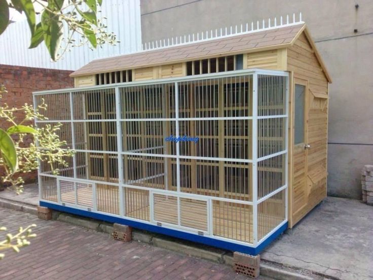 a small wooden bird cage on the side of a building next to a brick sidewalk