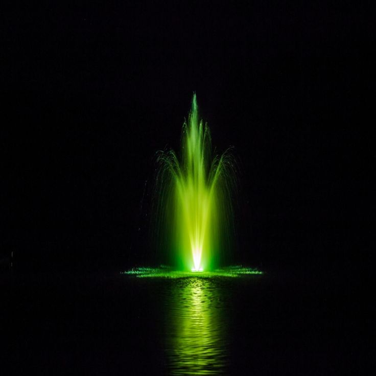 a green fountain is lit up in the dark