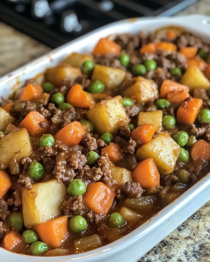 a casserole dish with meat and vegetables in it on a table next to a stove