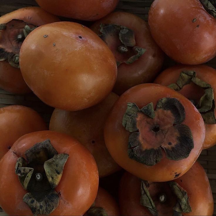 a pile of tomatoes sitting on top of a wooden table