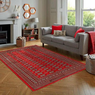 a living room filled with furniture and a red rug on top of a hard wood floor