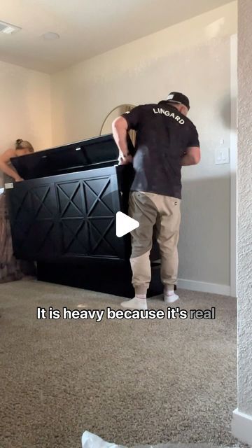 a man is moving a large black box in the living room