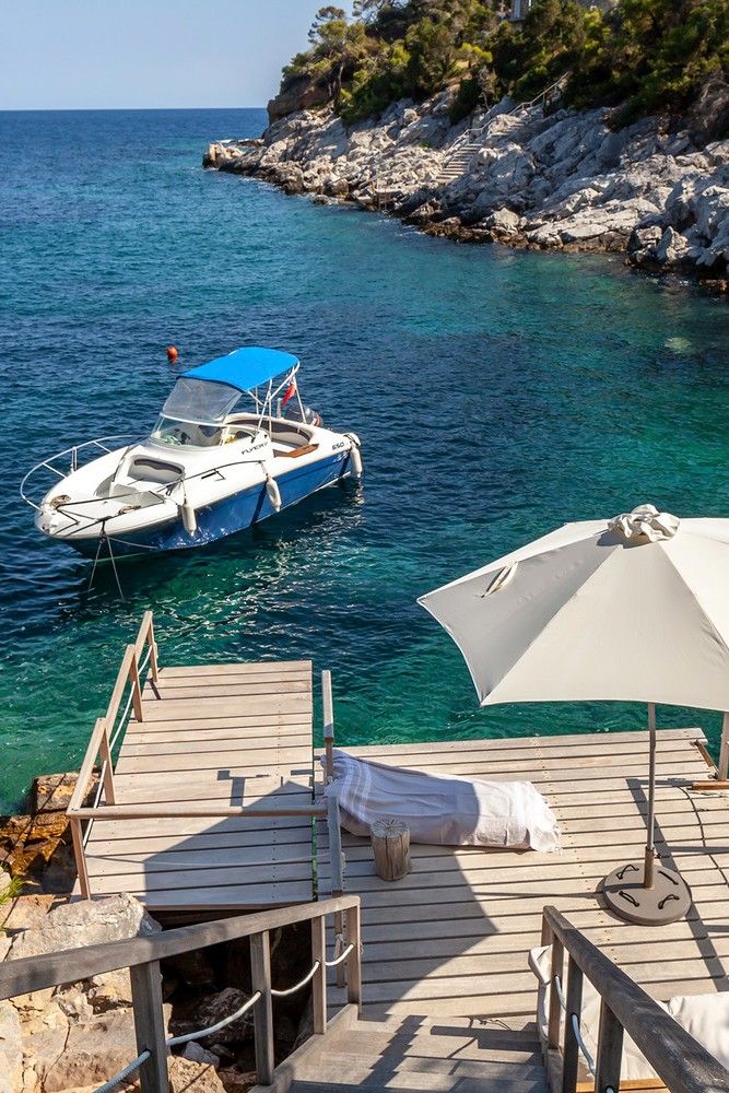 there is a boat that is in the water next to a dock with chairs and umbrellas