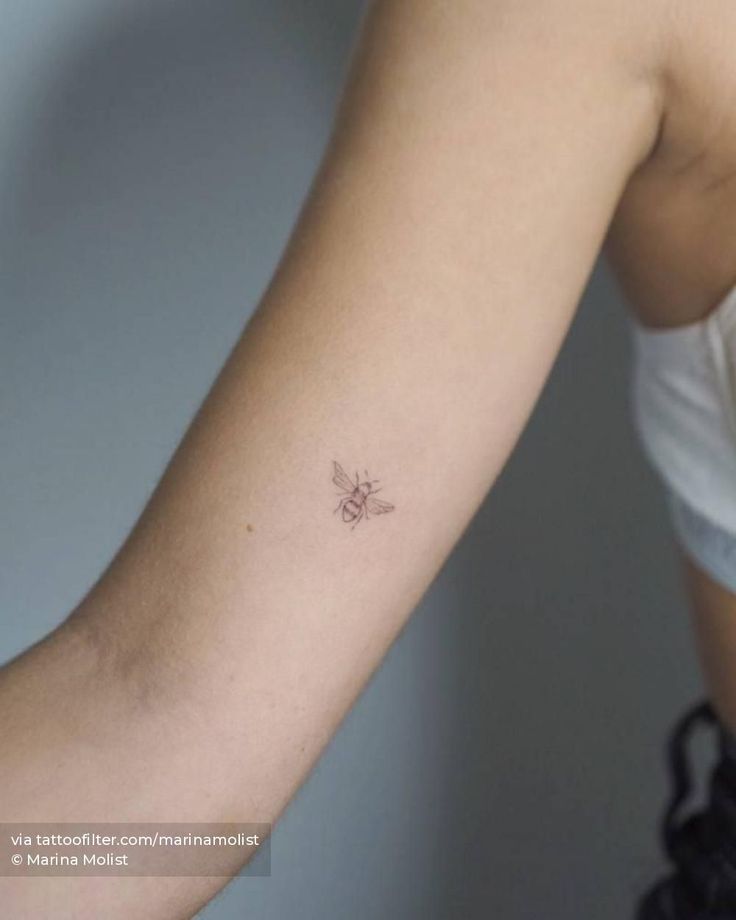 a woman's arm with a small bee tattoo on the left side of her arm