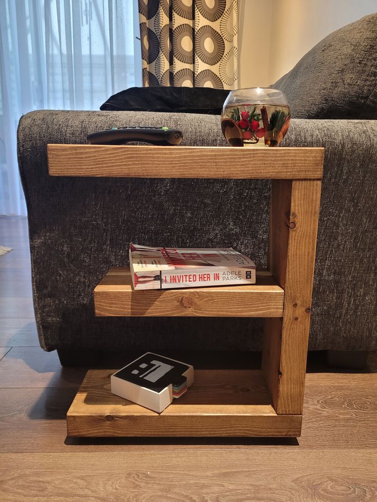 a wooden shelf with books on top of it in front of a couch and coffee table