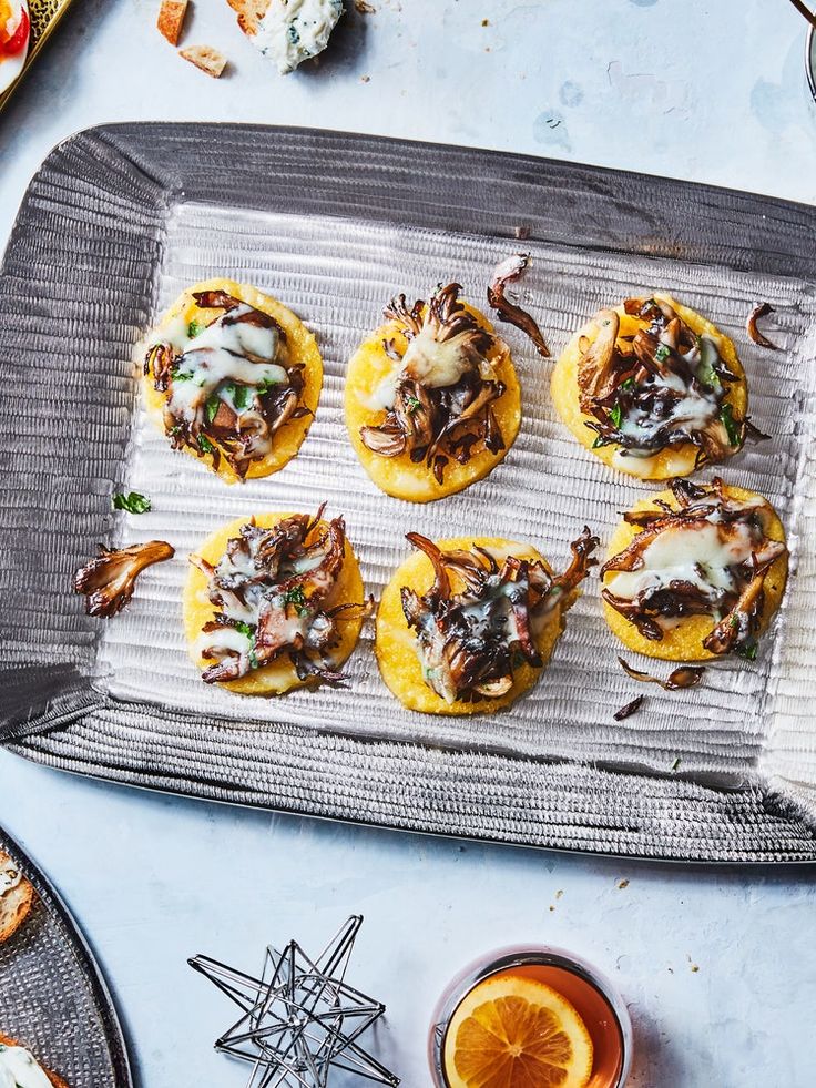 small appetizers are sitting on a tray next to an orange slice