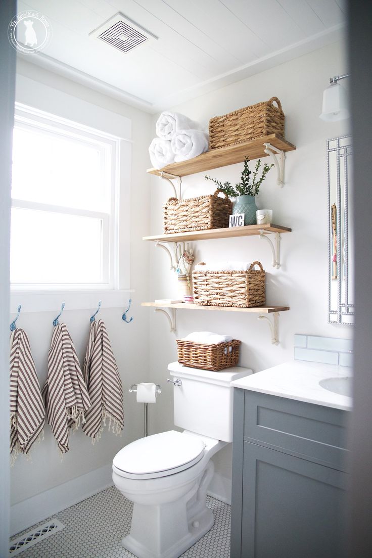 a white toilet sitting in a bathroom next to a window with towels hanging on it