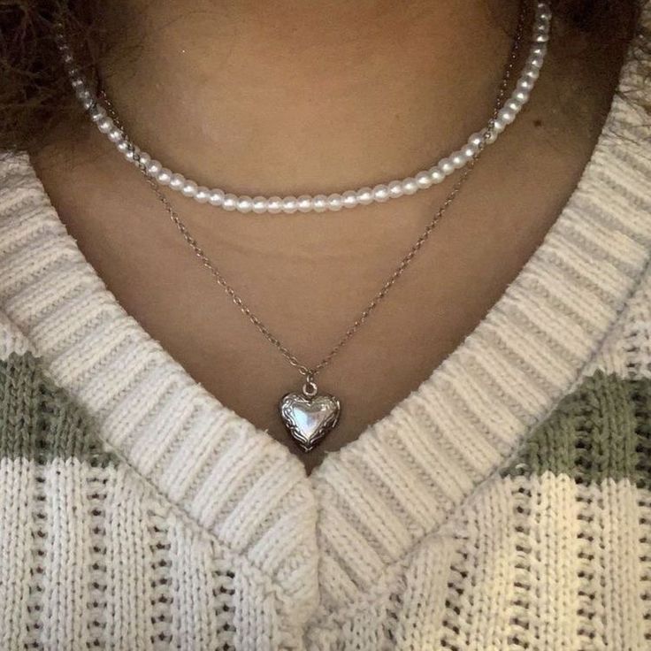 a woman wearing pearls and a necklace with a heart pendant