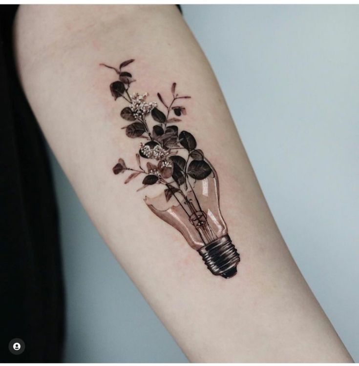 a light bulb tattoo on the arm with flowers in it and leaves growing out of it