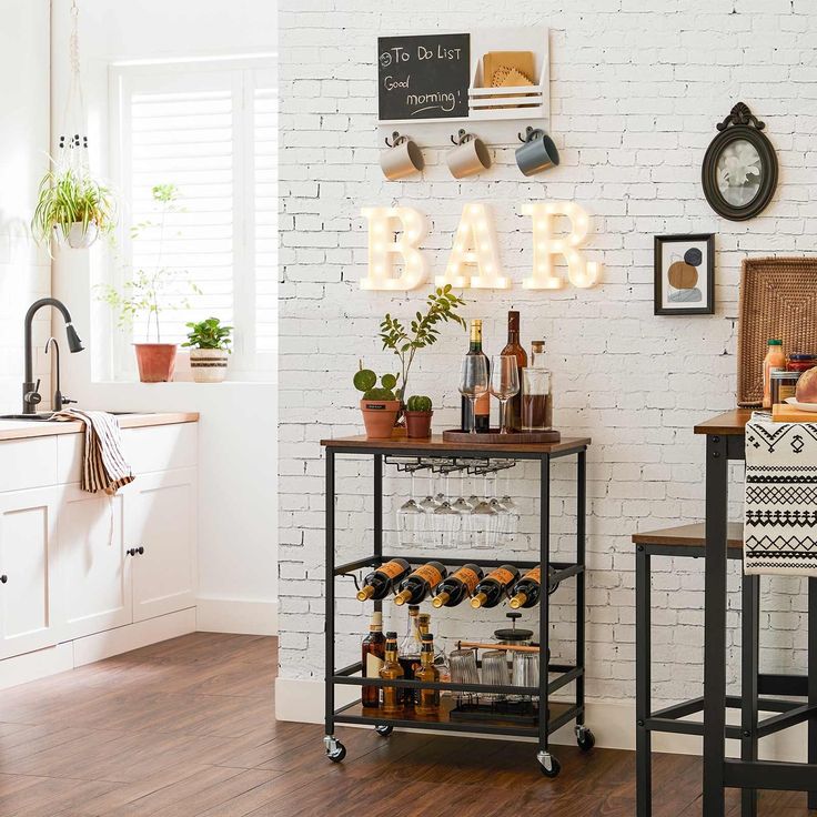 a bar cart with bottles and glasses on it in front of a white brick wall