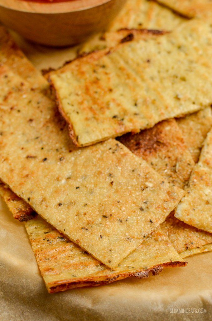 some crackers are sitting on a plate with a bowl of salsa in the background