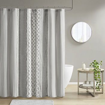 a white and gray shower curtain in a bathroom next to a bathtub with a round mirror