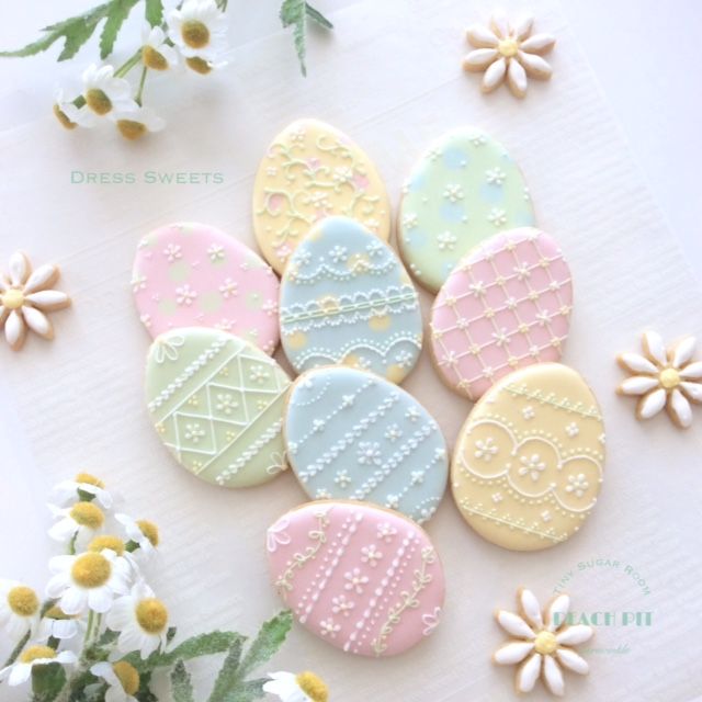 some decorated cookies sitting on top of a white table next to flowers and daisies