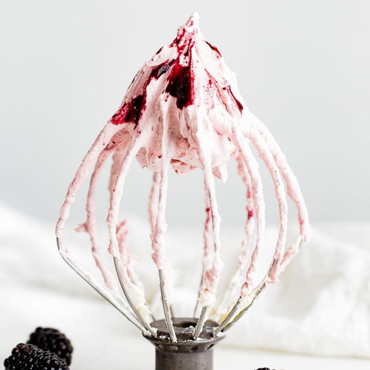 a whisk filled with whipped cream and blackberries