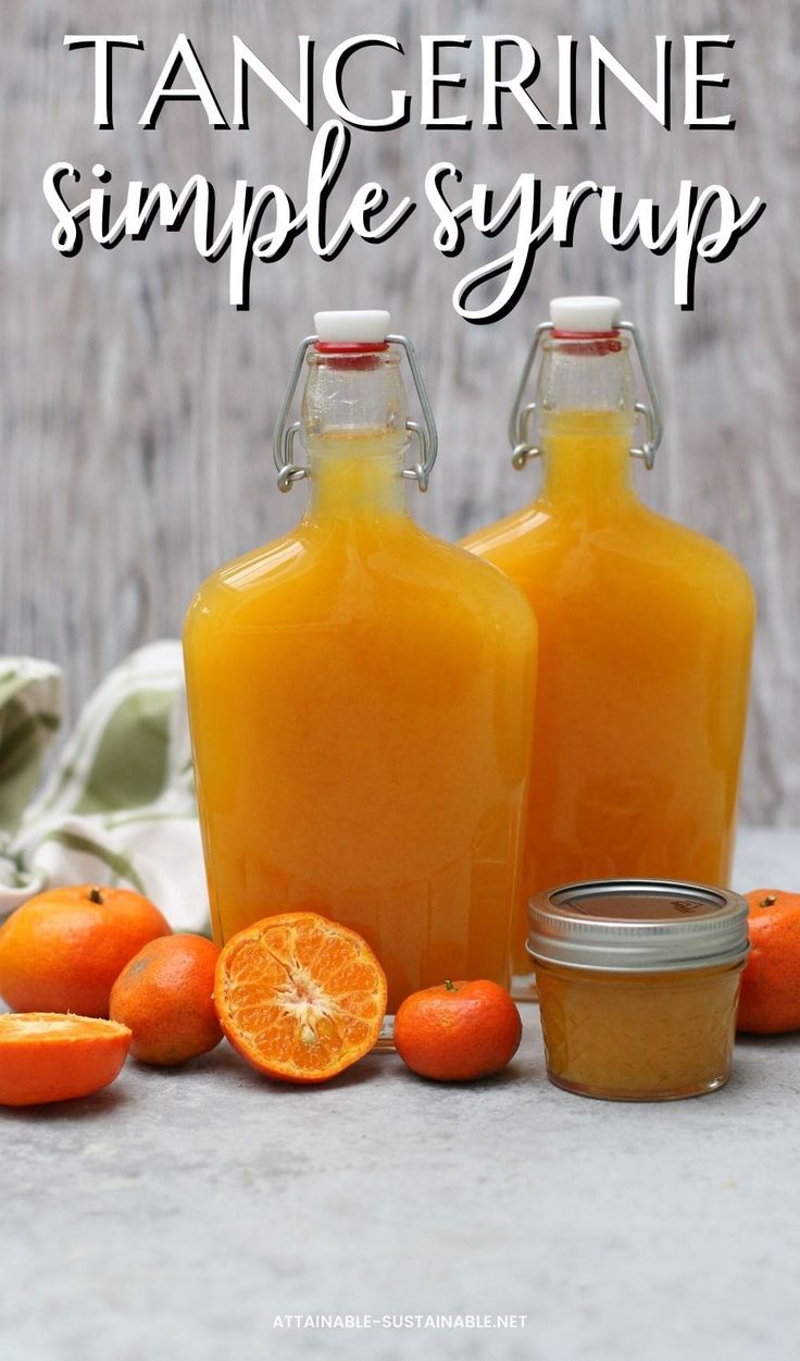 there are orange juice in two glass bottles next to some tangerines on the table