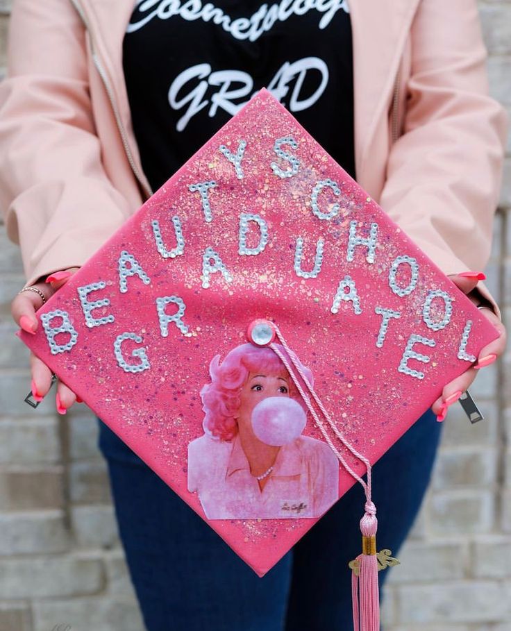 a woman holding a pink graduation cap that says, beauty and the beast on it