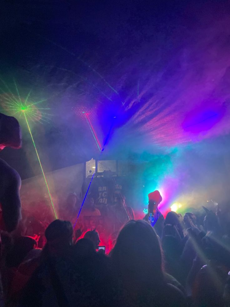 a group of people standing on top of a stage with colored lights in the background