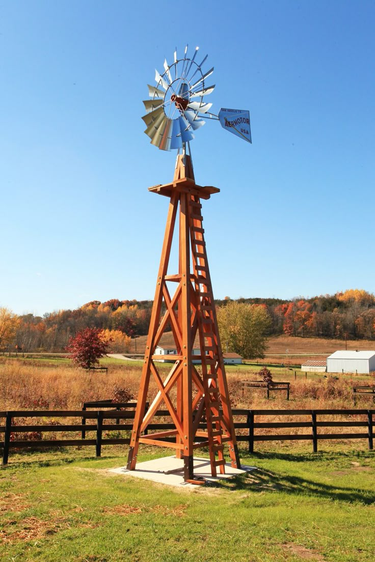 a wooden windmill sitting on top of a lush green field