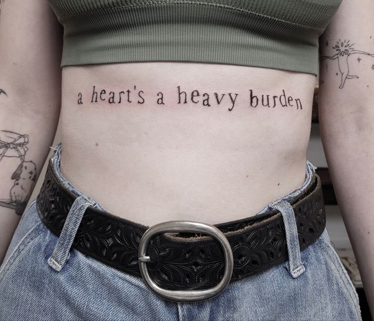 a woman's stomach with the words, a heart's a heavy burden written on it