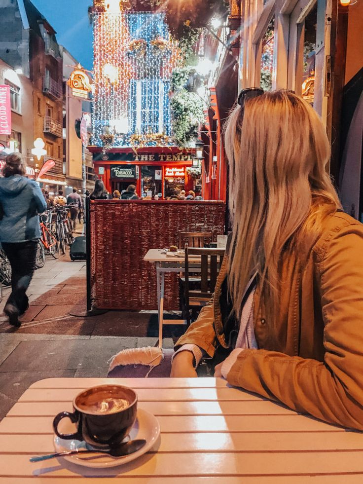 a woman sitting at a table with a cup of coffee