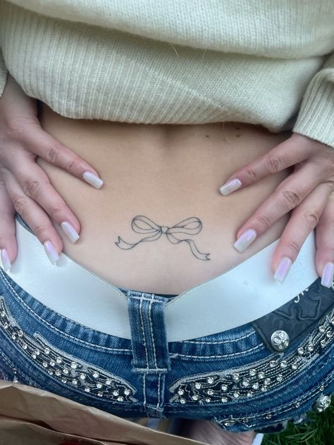 a woman's stomach with a bow tattoo on her lower body and bottom part