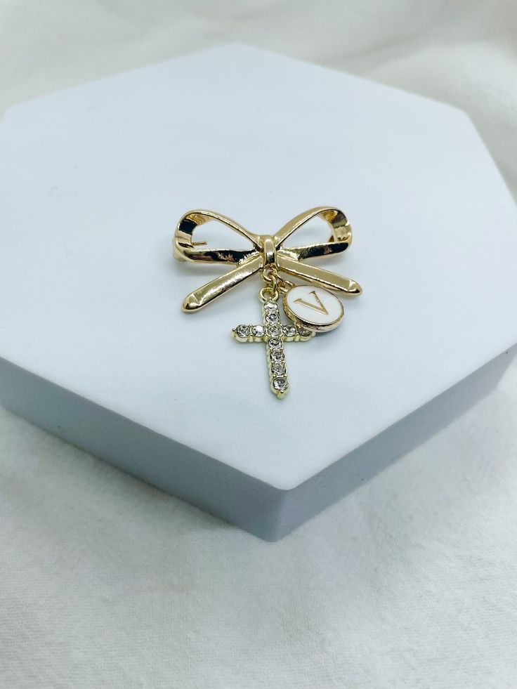 a white box with a cross and a gold bow brooch