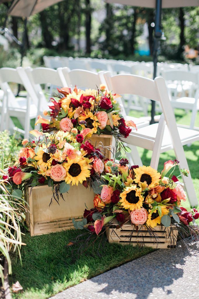 an arrangement of sunflowers, roses and other flowers in baskets on the grass