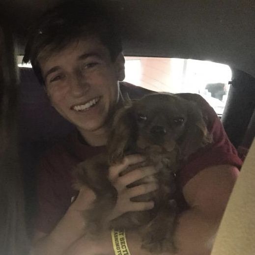 a man holding a small dog in his lap while sitting in the back seat of a car