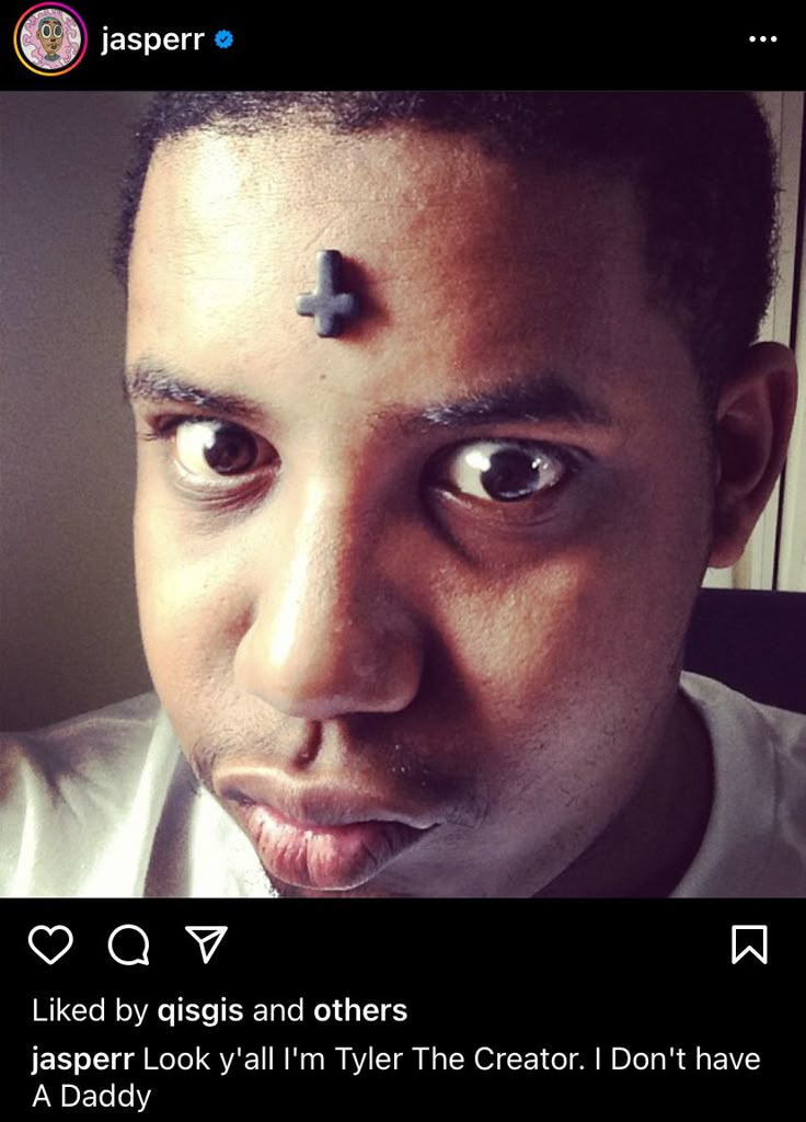 a man with a cross on his forehead looking at the camera and making a funny face