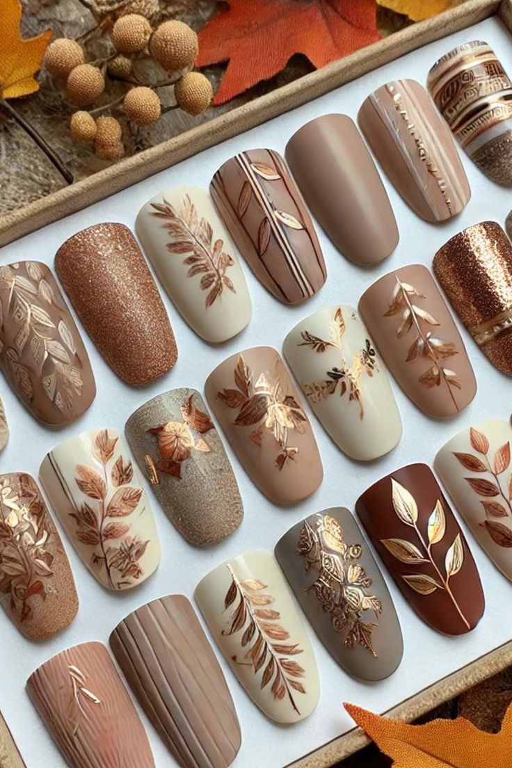 Achieve the perfect fall manicure with soft neutral nail polish, elevated by elegant leaf patterns, gold accents, and geometric designs! These autumn-inspired nails pair beautifully with cozy sweaters and seasonal vibes. 🍂✨ #FallNails #NailArt #NeutralNails #AutumnAesthetic Sweater Design Nail Art, Fall Nail Designs Rhinestones, Autumn Sweater Nails, Taupe Fall Nails, Brown Nails Autumn, Fall Glam Nails, Fall Nail Designs Pumpkin, Nails With Words On Them, Coffee Inspired Nails