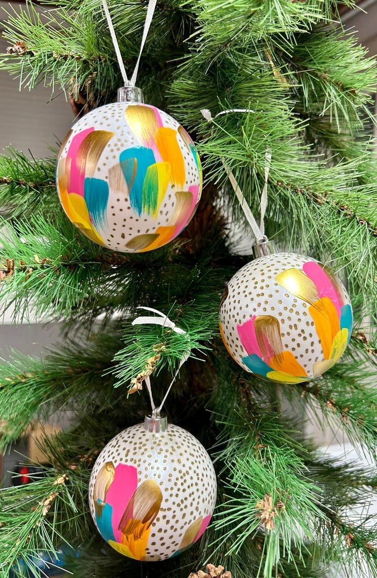 three ornaments are hanging from a christmas tree