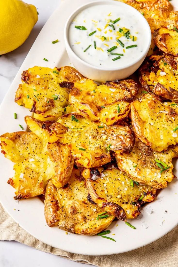 a white plate topped with potato wedges next to a small bowl of ranch dressing