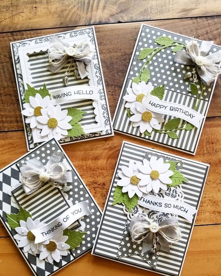 four cards with flowers on them sitting on a wooden table next to a pair of scissors