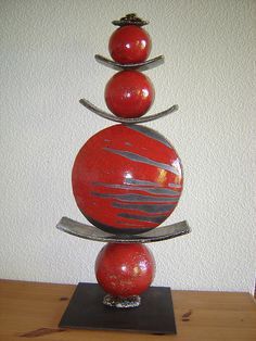 a red and black sculpture sitting on top of a wooden table