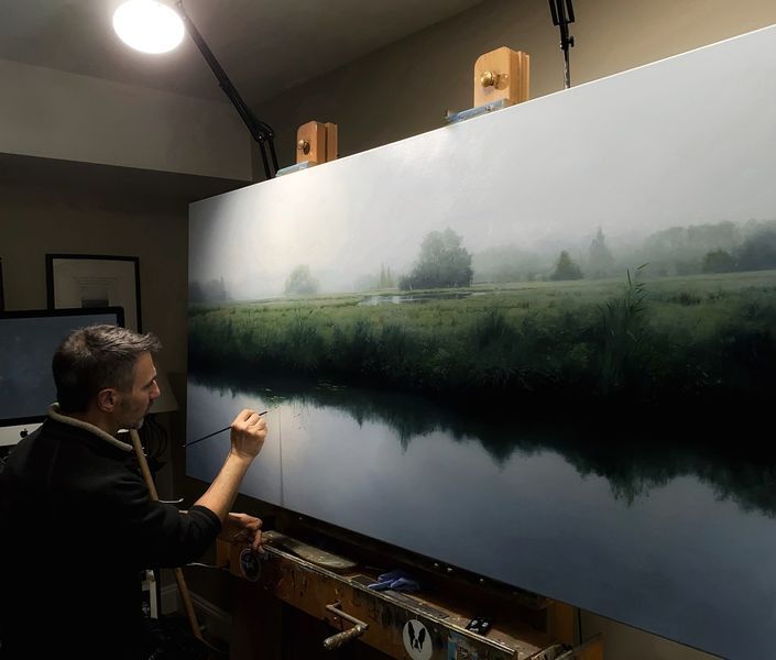 a man is painting a landscape on the easel in front of a large canvas