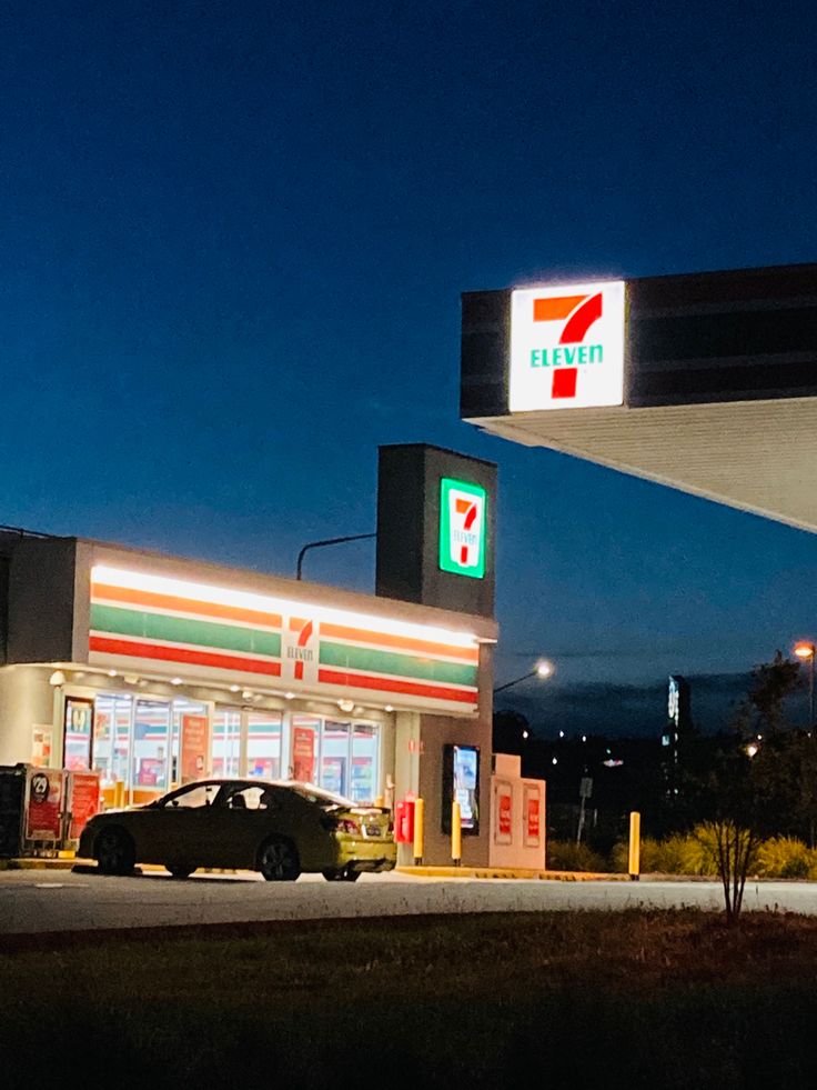 a car is parked in front of a gas station at night with the lights on