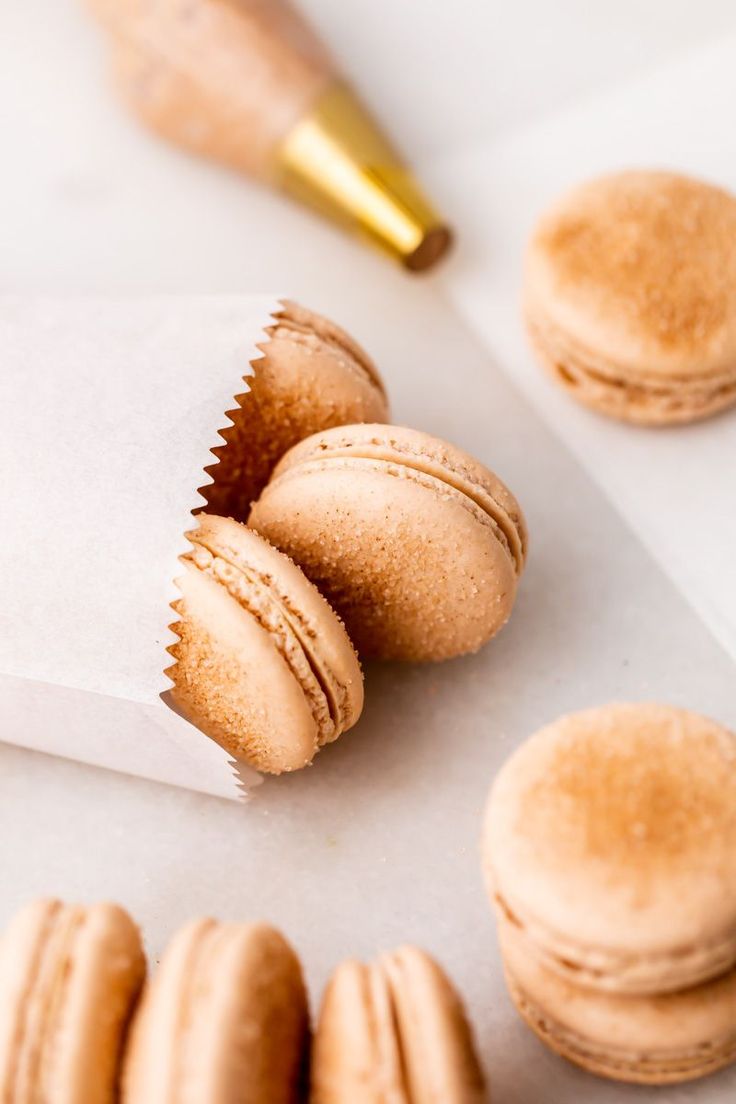 some macaroons are sitting on a piece of paper next to a gold pen