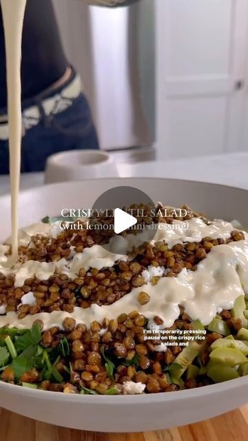 a person pouring dressing into a salad in a bowl