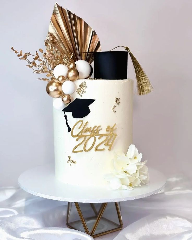 a white and gold graduation cake with decorations