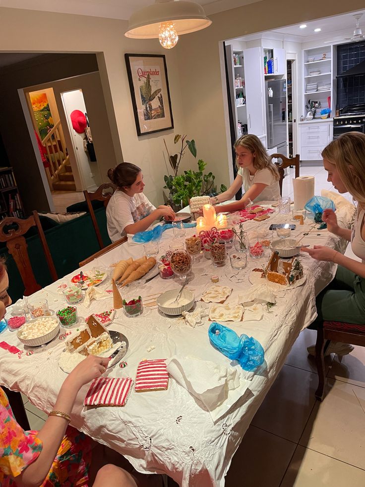 a group of people sitting around a table with food on it and candles in the middle