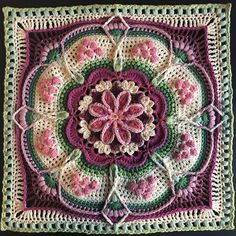 a crocheted square with pink and green flowers in the center on a black background